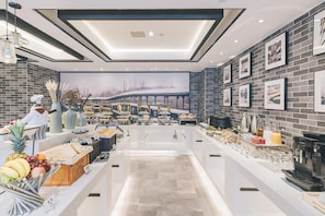A modern dining area with a central buffet, a large mural, and a brick wall with framed pictures. - Atour Hotel (Jiaxing)