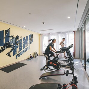A gym with exercise equipment, a wall with motivational text, and a large window. - Atour Hotel (Jiaxing)