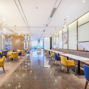 A modern interior with a long counter, yellow and blue chairs, and a polished marble floor. - Atour Hotel (Zhongshan)