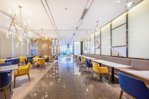 Uma sala de jantar moderna com mesas e cadeiras, piso lustroso e teto iluminado.