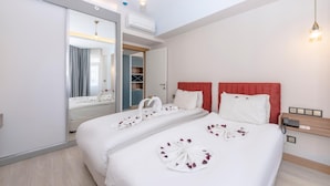 A hotel room with a large bed, a mirror, a wardrobe, and a bedside table with a phone. - Theluna Suite Hotel (Konyaalti)