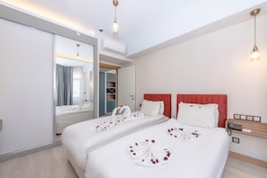 A hotel room with a large bed, a mirror, a wardrobe, and a bedside table with a phone. - Theluna Suite Hotel (Konyaalti)