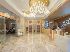 A modern hotel lobby with a marble floor, a reception desk, a digital screen, and a unique ceiling light fixture. - Lavande Hotel Wuhan Qushuilou of Xinhua Road (Wuhan)