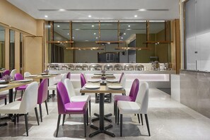 Uma sala de jantar moderna com várias mesas e cadeiras, serviço de buffet e design limpo e contemporâneo.