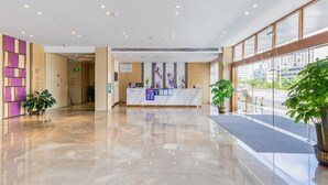 Ein Hotel-Empfangsbereich mit Marmorboden, einer Rezeption und Topfpflanzen.