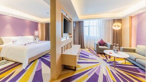 Ein Hotelzimmer mit Bett, einer Couch, einem Couchtisch und einem Fernseher.