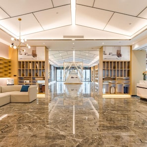 A hotel lobby with a central staircase, marble flooring, and built-in shelving units. - Atour Hotel Wangting Suzhou (Suzhou)