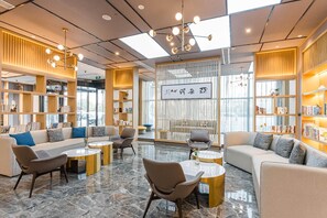 Uma área de estar moderna com sofás, cadeiras e uma mesa de centro.