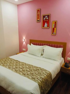 A hotel room with a bed, a bedside table, and a wall with three framed pictures. - Hotel Silver Retreat (Gandhinagar Gujrat)