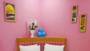 A bedroom with a bed, pink walls, and framed pictures. - Hotel Silver Retreat (Gandhinagar)
