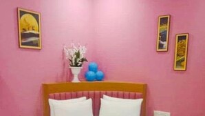A room with a bed, pink walls, and framed pictures. - Hotel Silver Retreat (Gandhinagar)