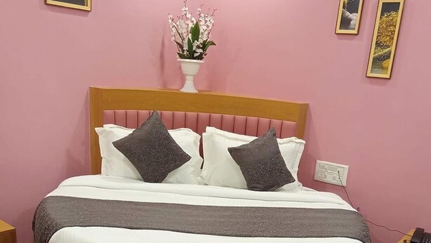 A bedroom with a round bed, a bedside table, a nightstand, and a wall-mounted telephone. - Hotel Silver Retreat (Gandhinagar)