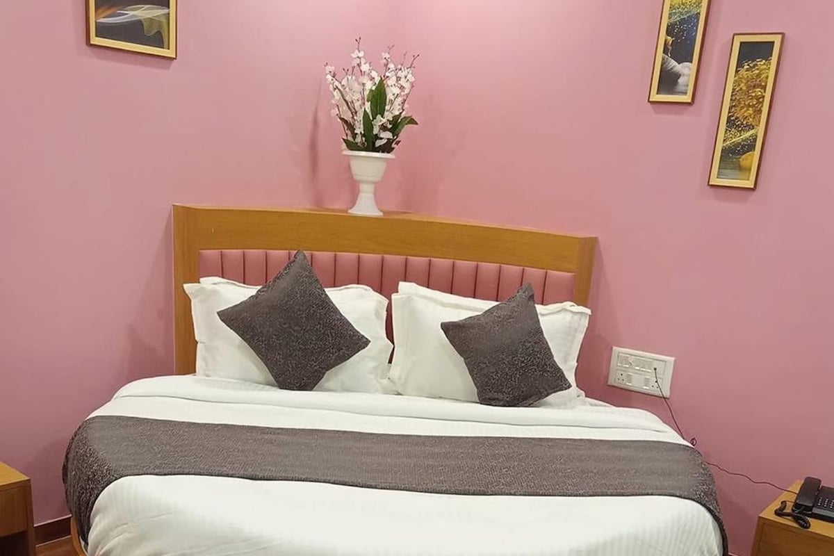 A bedroom with a round bed, a bedside table, a nightstand, and a wall-mounted telephone.