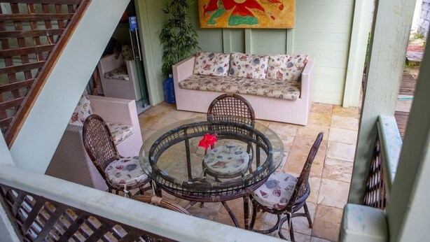 A covered outdoor seating area with a sofa, wicker chairs, and a glass table. - Pousada Sol e Mar - Noronha (Fernando de Noronha)