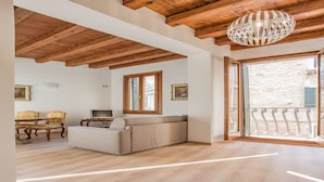 A spacious living area with a wooden ceiling, a sofa, a television, and a dining set. - Venezia - Calle Campanile 3076 (Venice)