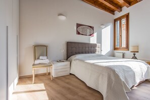 Ein Schlafzimmer mit Bett, Nachttisch, Sessel und Fenster.