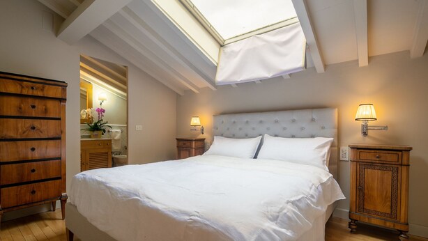A bedroom with a skylight, a bed, bedside tables, a dresser, and a mirror. - San Jacopo Top (Florence)