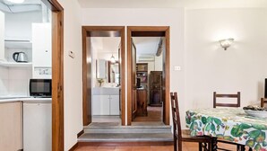 A kitchen with a dishwasher, a television, and a dining area with a table and chairs. - Pratello Centrale e Funzionale Apartment (Bologna)