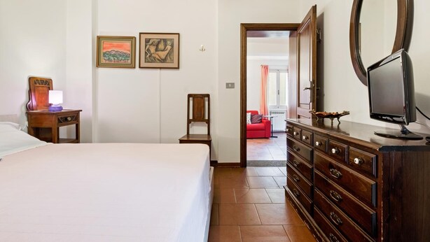 A hotel room with a bed, dresser, mirror, and artwork on the wall. - Pratello Centrale e Funzionale Apartment (Bologna)