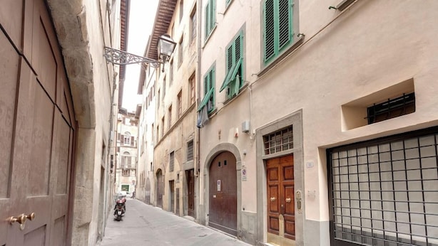 A narrow street with buildings on either side, featuring a motorbike in the distance. - Mamo Florence - Velluti Apartment (Florence)