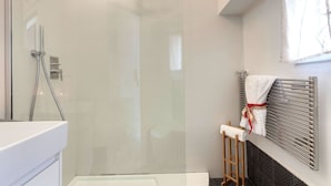 A modern bathroom with a glass shower enclosure, a white sink, and a towel rack with a towel. - Mamo Florence - Velluti Apartment (Florence)