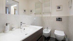 A modern bathroom with a large sink, bidet, and toilet. - Suite Jasmine (Florence)