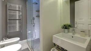A modern bathroom with a glass-enclosed shower, a white sink, and a mirror above it. - Mamo Florence - St Elizabeth Loft Apartment (Florence)