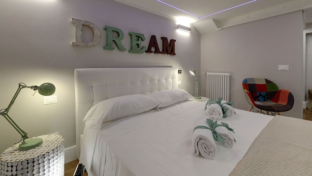 A bedroom with a bed, a desk lamp, a chair, and a wall with the word 'DREAM' spelled out. - Mamo Florence - St Elizabeth Loft Apartment (Florence)