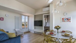 A modern living room with a dining area, a television, and a balcony. - Penthouse With big Terrace in Oltrarno-hosted by Sweetstay (Florence)