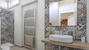 A bathroom with a toilet, a bathtub, a towel rack, and a sink with a mirror. - Penthouse With big Terrace in Oltrarno-hosted by Sweetstay (Florence)