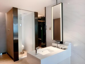 Une salle de bain moderne avec un grand miroir, un lavabo blanc et une douche à l’italienne.