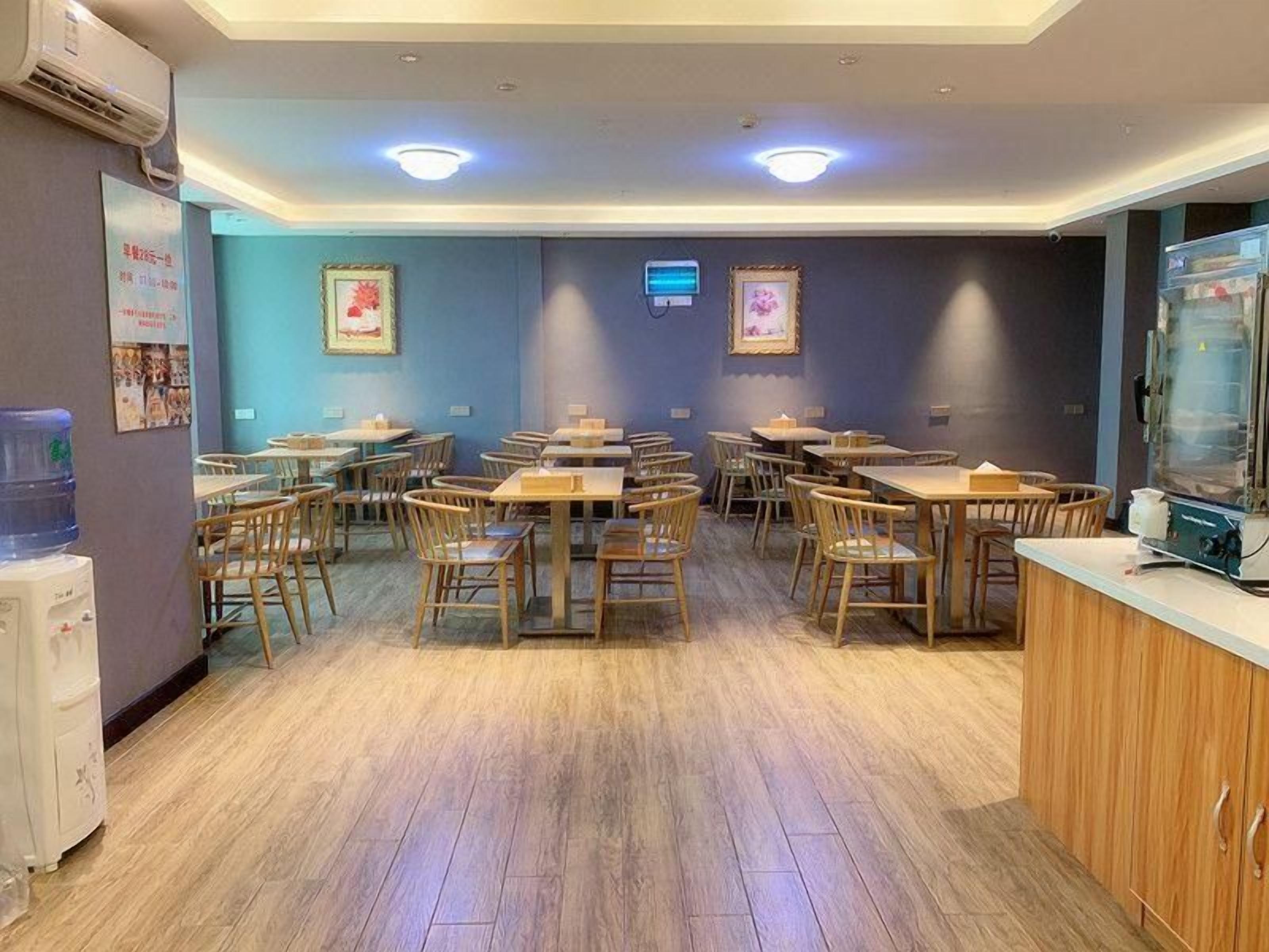 A dining area with multiple tables and chairs, a water dispenser, and a refrigerator.