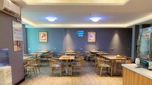 A dining area with tables and chairs, a water dispenser, and a refrigerator. - Borrman Hotel (Huizhou)