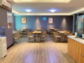 Un espace repas avec des tables et des chaises, un distributeur d’eau et un réfrigérateur.