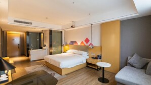 A modern hotel room with a bed, bedside table, lamp, and a sofa. - Borrman Hotel (Huizhou)
