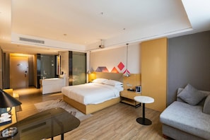 Une chambre d’hôtel moderne équipée d’un lit, d’une table de chevet, d’une lampe et d’un canapé.