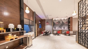 A modern dining area with a long table and chairs, a kitchen area with appliances, and a TV screen. - Borrman Hotel Hengyang Huaxin Caixia Street (Hengyang)