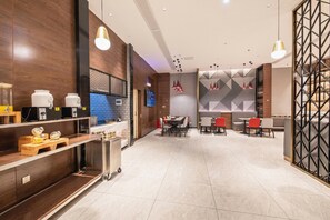 A modern dining area with a long table and chairs, a kitchen area with appliances, and a TV screen. - Borrman Hotel Hengyang Huaxin Caixia Street (Hengyang)