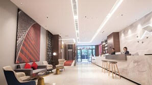 A modern hotel lobby with a reception desk, seating area, and a large abstract wall art piece. - Borrman Hotel Hengyang Huaxin Caixia Street (Hengyang)