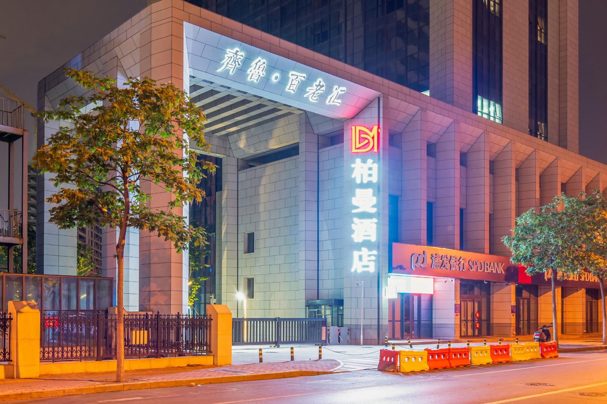 A modern building with large signage, a gated entrance, and a street view.