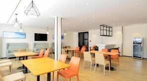 A modern dining area with tables and chairs, a flat-screen TV, and a refrigerator. - City Comfort lnn Lijiang Transportation Station (Lijiang)