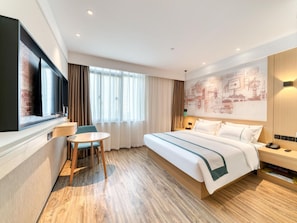 A hotel room with a bed, a desk, a chair, a TV, and a large window with curtains. - City Comfort lnn Lijiang Transportation Station (Lijiang)