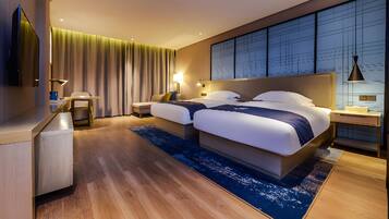 A modern hotel room with a large bed, bedside tables, a desk, and a view of the cityscape.