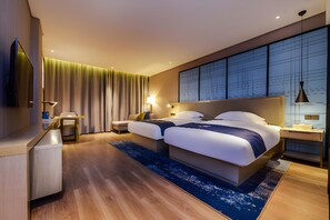 A modern hotel room with a large bed, bedside tables, a desk, and a view of the cityscape through the windows. - Echarm Hotel (Qianxinan Buyei and Miao)