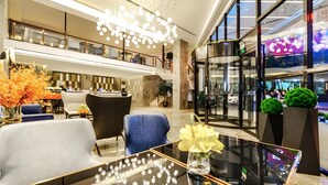 Een moderne lobby met een glazen salontafel, een zithoek en een trap.