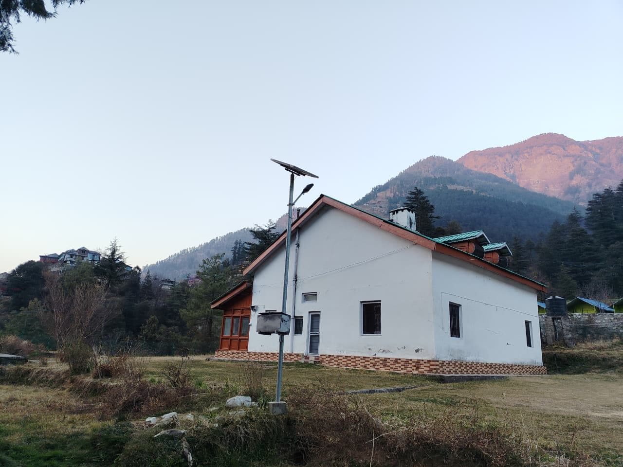A white building with a red roof, a solar panel, and a small window.
