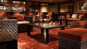 A bar area with wicker furniture, a patterned carpet, and a bar stocked with bottles. - JAZ Crown Jubilee Nile Cruise - Thursday VIA Luxor 7 & 4nts - Monday VIA Aswan 3nts (Luxor)