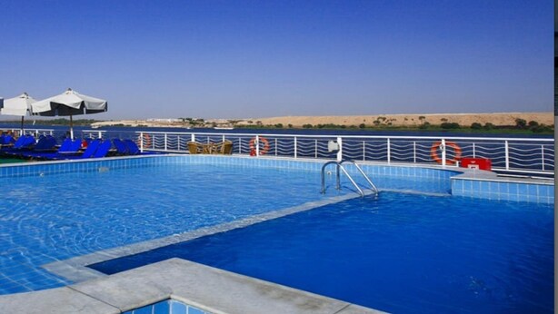 A swimming pool with blue tiles, a metal railing, and a desert landscape in the background. - JAZ Crown Jubilee Nile Cruise - Thursday VIA Luxor 7 & 4nts - Monday VIA Aswan 3nts (Luxor)