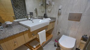 A modern bathroom with a sink, mirror, towel rack, toilet, and a shower area. - Izgrev Hotel (Struga)
