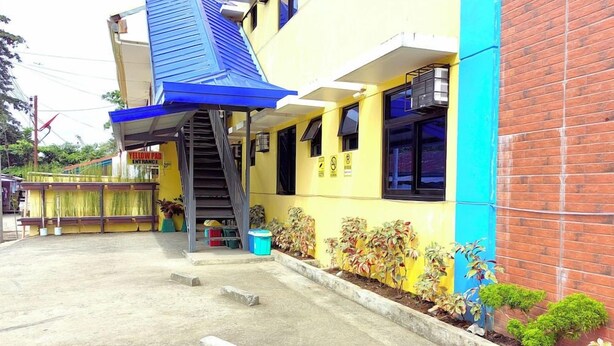 Un edificio con una facciata gialla, un tendone blu e una scalinata che conduce all'ingresso.